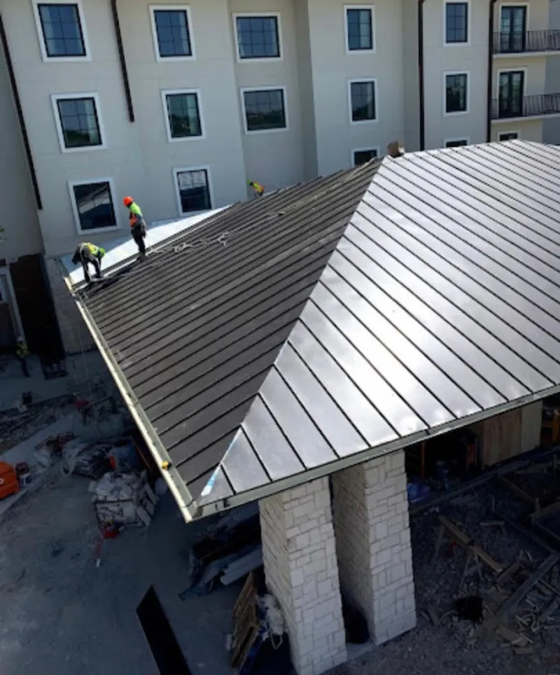 Crew installing standing seam metal roof panels on a commercial project in Stillwater